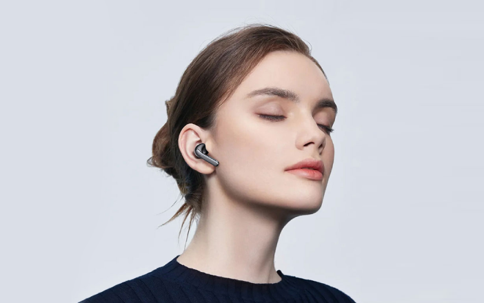 Pair of earbuds resting beside their charging case on a dark surface